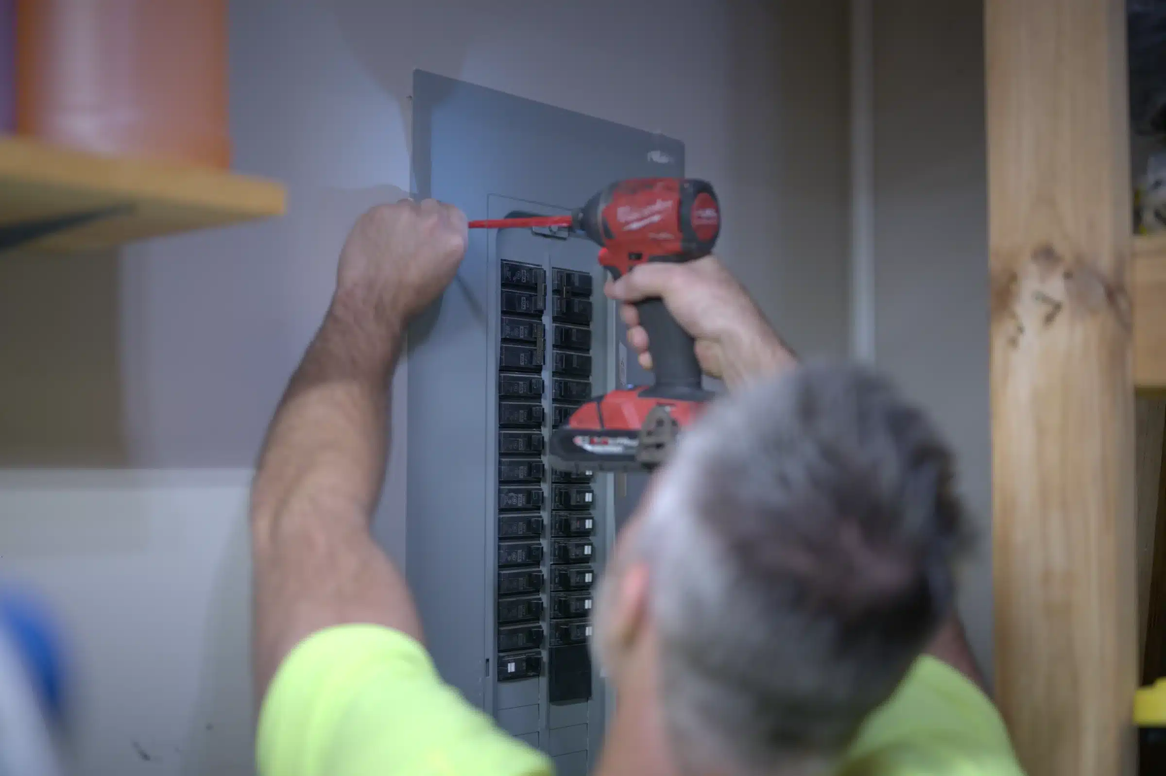 Electrician using a power drill to upgrade an electrical panel in a Kansas City home, emphasizing electrical safety and efficiency.