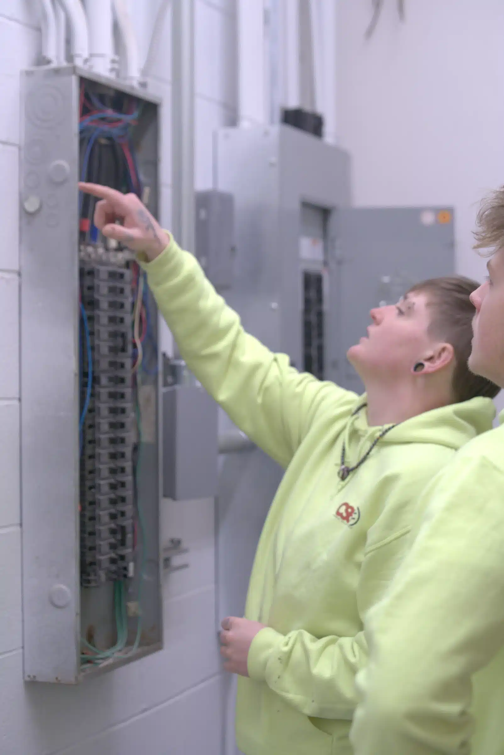 Electricians inspecting a circuit breaker panel, focusing on safety and efficiency in electrical installations, relevant to outlet and switch upgrades in Kansas City, MO.